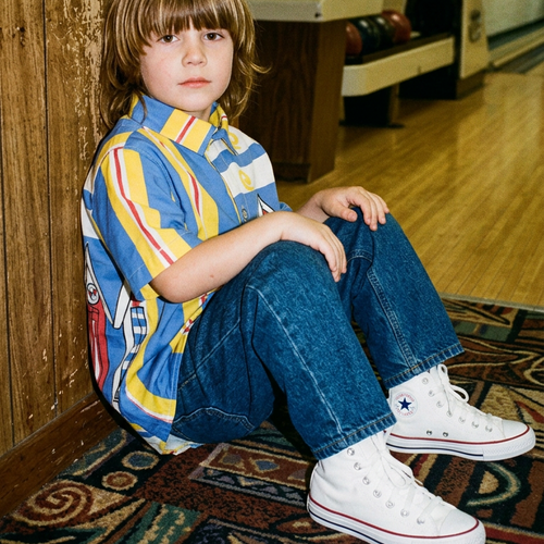 Child sitting on a bowling alley floor with vintage bowling alley equipment in the background