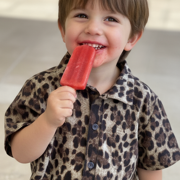 Child wearing a  Alfie leopard print Party shirt holding a red ice block.